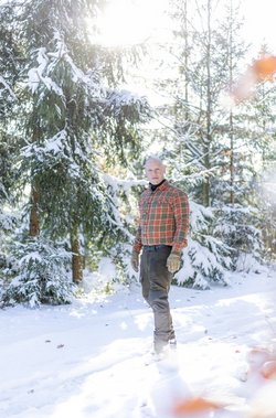 Bildbeschreibung: Frank Schmidt im Winterwald (mit Schnee bedeckte Bäume im Hintergrund, stehend, 